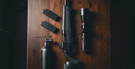 A PCP air rifle, scope and air tank laid out for a new owner.