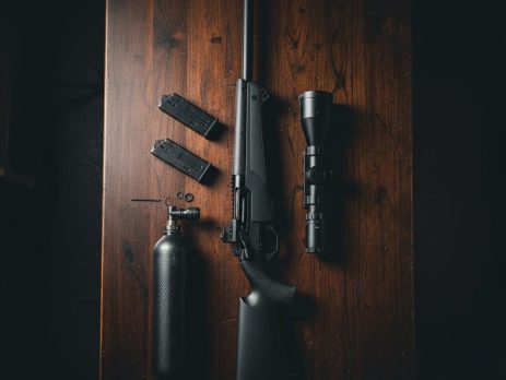 A PCP air rifle, scope and air tank laid out for a new owner.